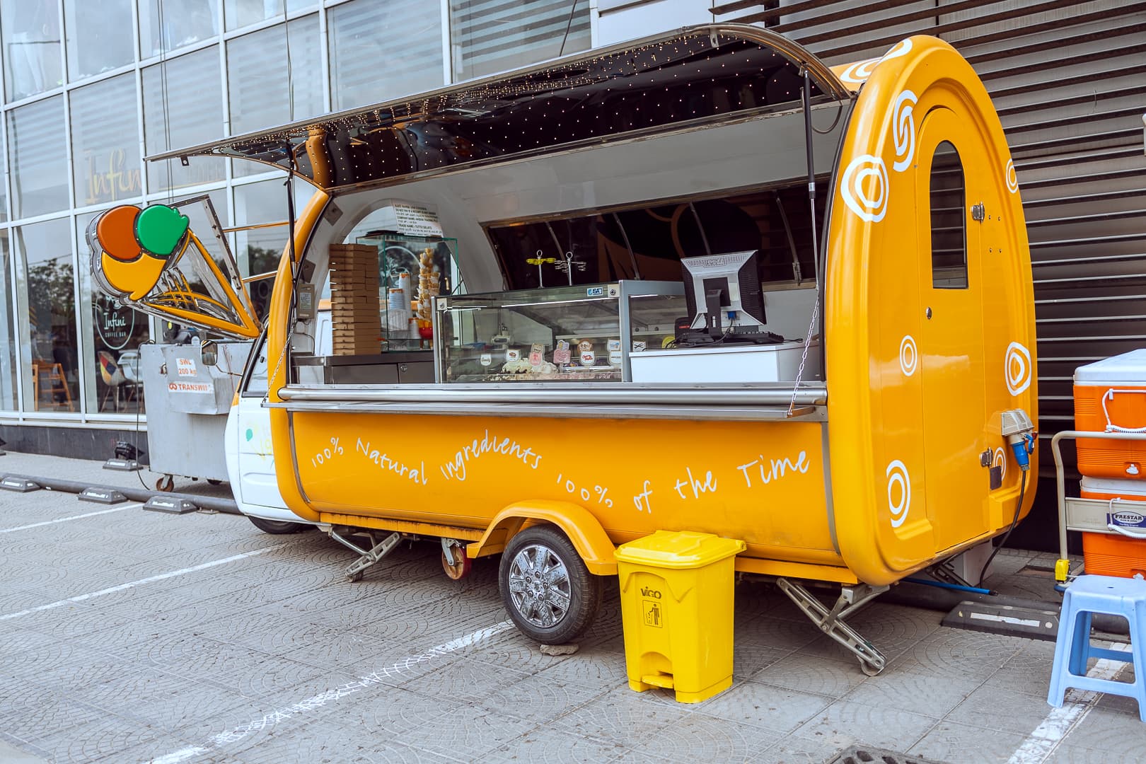 Bright yellow Tutto Gelato mobile food cart truck parked outside