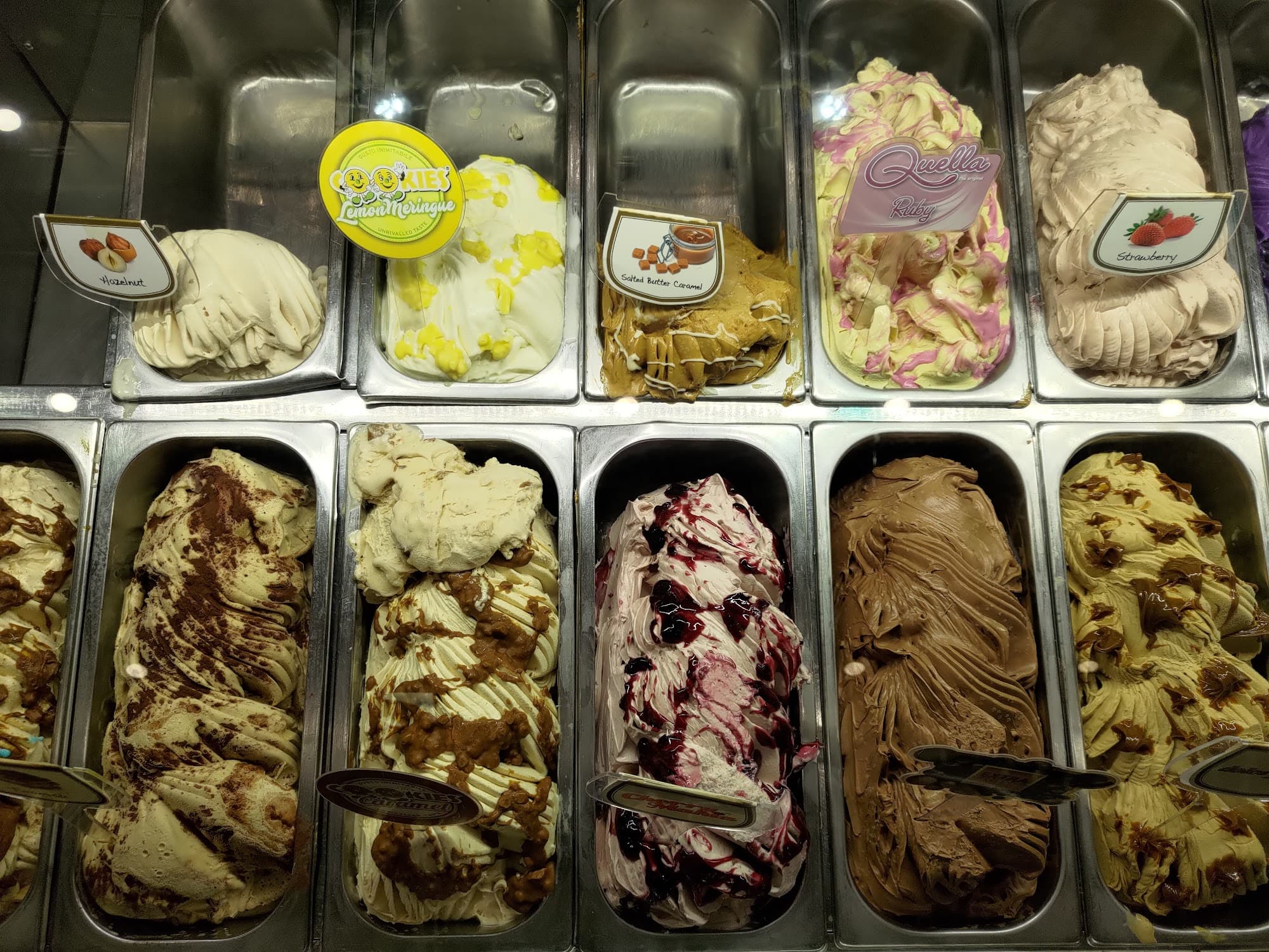 Detailed view of artisanal gelato pans showcasing variety of flavors like strawberry and caramel