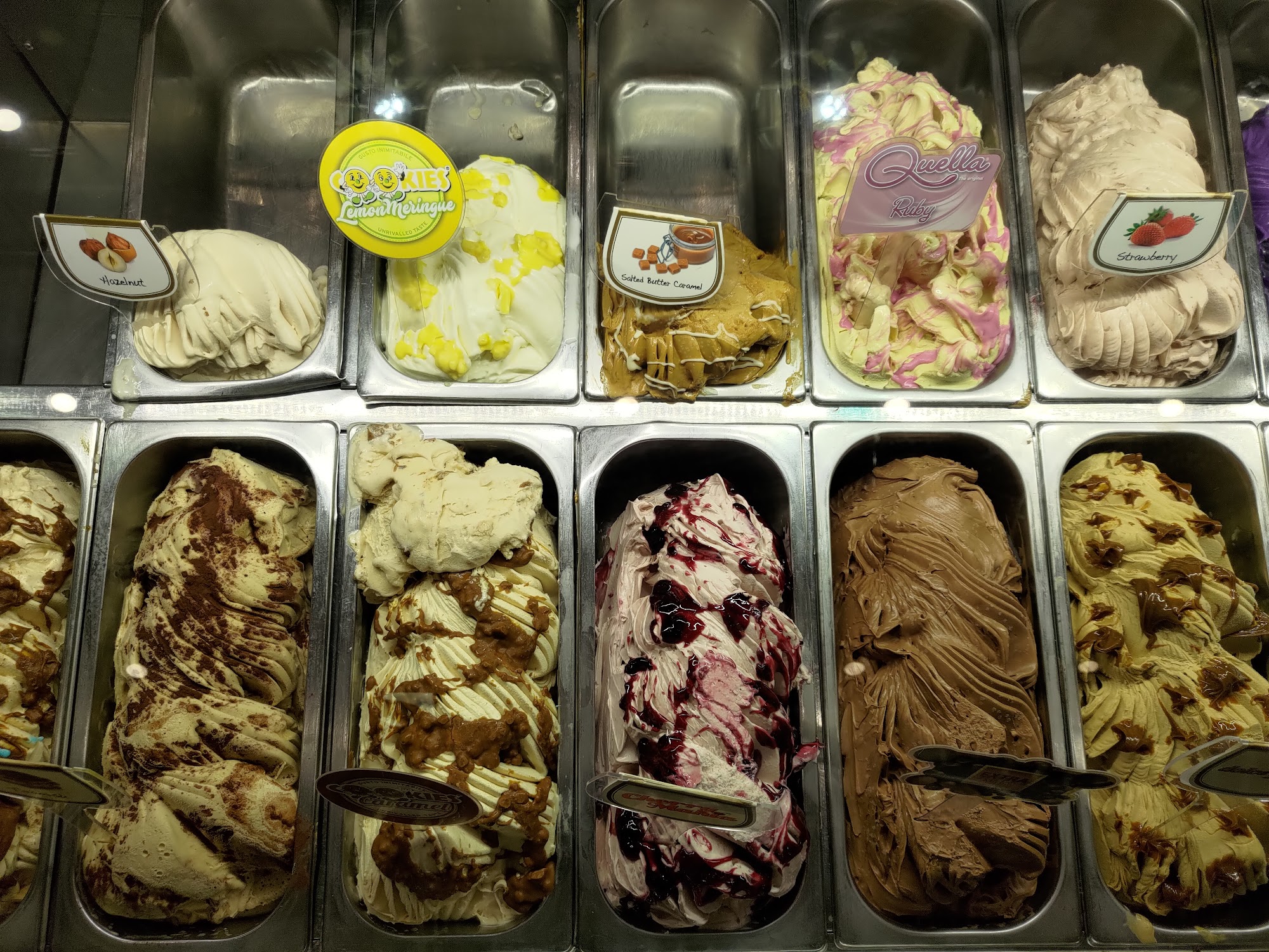 Detailed view of artisanal gelato pans showcasing variety of flavors like strawberry and caramel